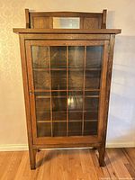 Front view showing full cabinet with glass door and mirrored crest