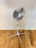 Full view of white pedestal fan standing on hardwood floor