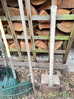 group of rakes, cultivator, splitters against woodpile