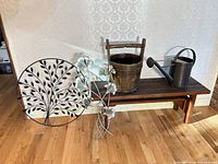 Full lot on floor: bench, wall art pieces, bucket, watering can