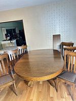 Oak dining table with six chairs visible, leaf leaning against wall