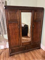 Front view showing full piece with mirrored center door and bottom drawers