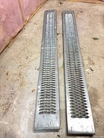 Pair of galvanized steel loading ramps on floor, full view