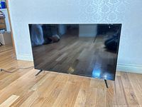 Front view of 43-inch RCA TV on floor showing screen and stand