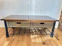 Full view of coffee table angled, wood top, wicker drawers, metal legs