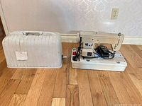 Sewing machine in base beside detached lid