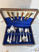 Open wooden case showing knives and assorted utensils