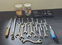 All items laid out: wrenches, screwdriver, bit case, fastener jars, knife