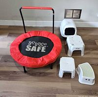 Rebounder with red pad installed, handle upright, three stools and litter box grouped