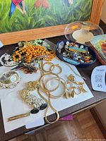 Overview of jewellery spread on table with watch, necklaces, earrings, bead strands and dish