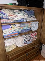 Front view of cabinet shelves filled with folded linens