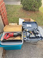 Lot overview showing totes with reciprocating saw in box and case with drill and jigsaw