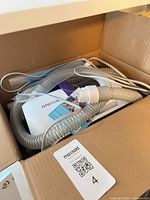 Box interior showing Oneisall vacuum components including coiled hose and manual