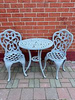 Full view of table and two chairs against brick wall