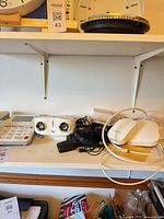 Shelf view showing corded telephone, iLuv speaker, satellite speakers, mesh routers and cables