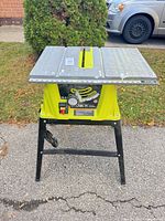 Front view showing Ryobi branding, 15-amp rating, power switch, rip fence slot
