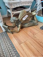 Full view of fairy sculpture on floor showing reading pose and wings