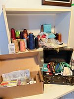 Overall view of shelving showing thread cones, mini sewing machine, boxed kit and chest