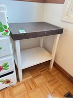 Full view of two-tone wooden side table against wall