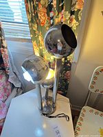 Full view of chrome three-tier table lamp on table
