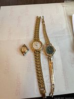 Front view of three watches showing dials and missing strap on smallest watch