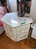 Full view of nightstand showing hexagonal top, doors, handles, and finish