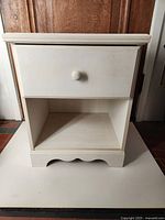 Front view of white nightstand showing drawer and open shelf