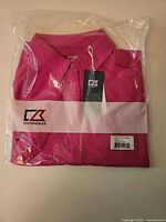 Folded berry pink Cutter & Buck women’s golf shirt sealed in plastic with tags