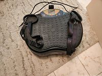 Top view of vibration platform showing textured surface, control panel, straps, power cord