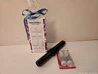 Gift-wrapped Goldwell shampoo and conditioner pack beside Conair curling iron and two refill cartridges