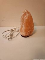 Front view of Himalayan salt lamp showing crystal, base and attached power cord