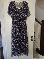 Full front view of navy print chiffon maxi dress hanging on door