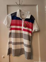 Front view of Puma women’s striped golf polo shirt with tags visible