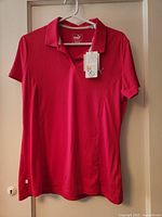 Front view of berry Puma golf polo showing tags and placket