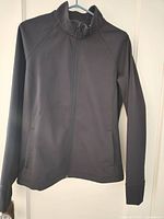 Front view of black Under Armour full-zip jacket on hanger