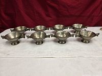 All eight nickel silver dragon-handled bowls arranged