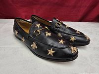 Top and side view of both loafers showing embroidery and horsebit