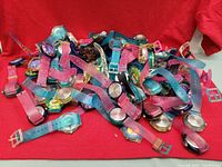 Pile of colorful plastic kids wrist watches on red fabric