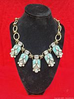 Full view of necklace on display bust showing gold-tone chain and five pendants