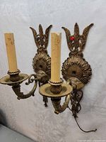 Front view showing both brass sconces with candle sleeves and ornate backplates