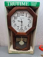 Front view of octagonal wall clock in original box
