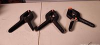 three black nylon spring clamps on table