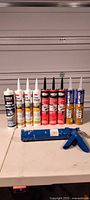 Group shot of all sealant tubes and caulk gun arranged on table