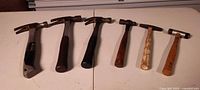 Six hammers lined side by side on table