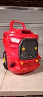 Front angled view of red toy truck cart showing grille, headlights and wheels