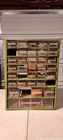 Front view of green raaco cabinet showing 32 clear drawers filled with hardware