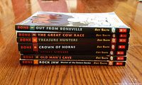 Stack of seven Bone graphic novels showing spines and titles