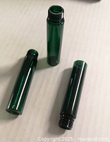 Three dark green plastic screw-neck vials shown close-up