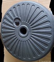 Top view of black plastic 20" fillable patio umbrella base showing ribbed surface, central pole sleeve and fill plug
