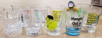 Front view of nine of the shot glasses showing graphics and faceted glass